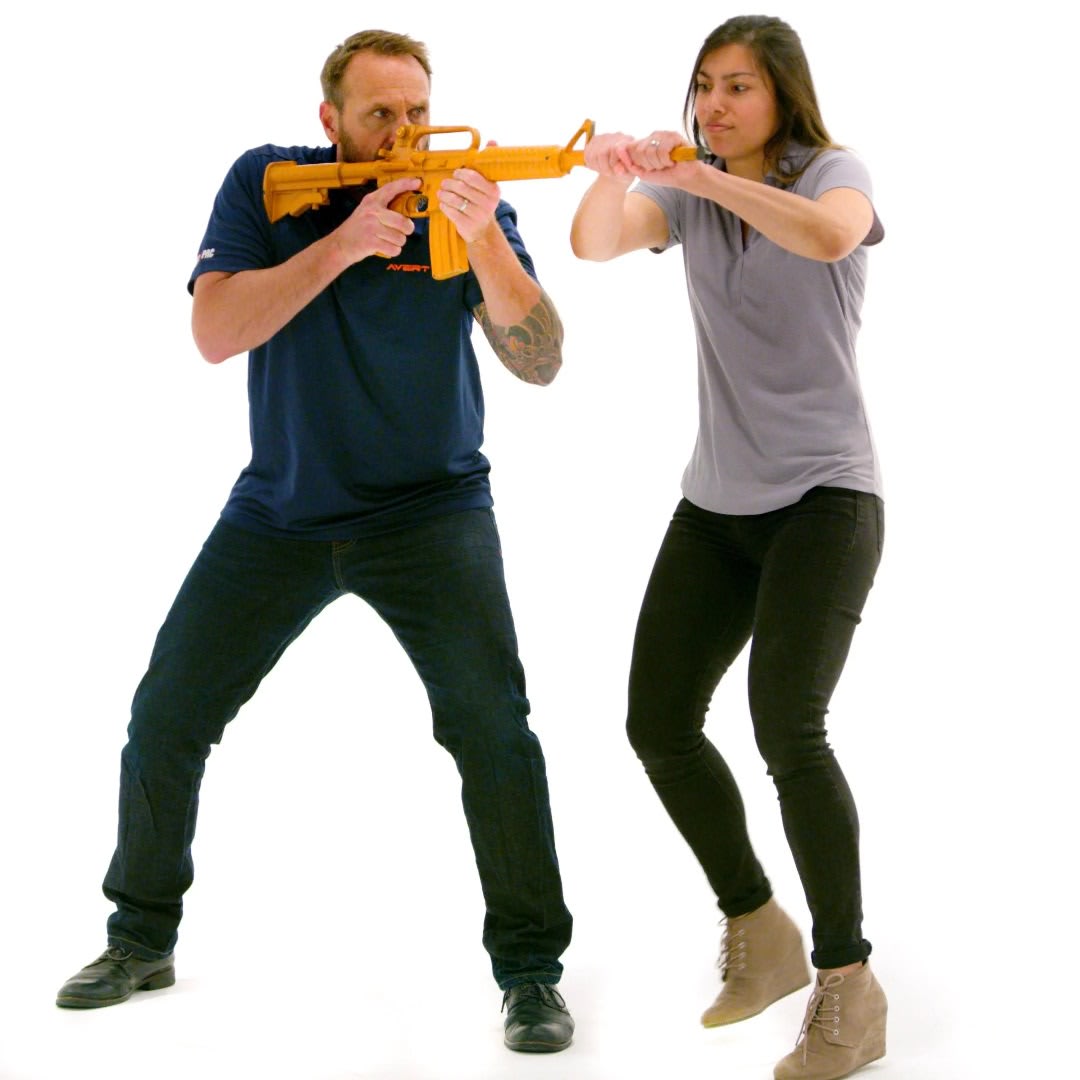 Instructor and participant practice an active-violence response technique with an orange training rifle